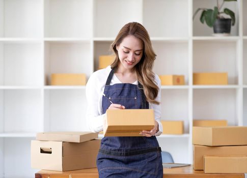 Portrait of Asian young woman SME working with a box at home the workplace.start-up small business owner, small business entrepreneur SME or freelance business online and delivery concept..