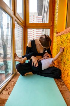 family sport. mother teaches son to do yoga. Helps with stretching. On the balcony In a home apartment.