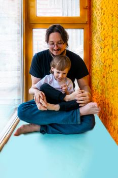 family sport. father teaches son to do exercises. Helps with stretching. On the balcony In a home apartment.