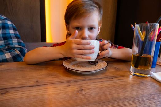 Little boy drinking from a cup tea in a cafe. High quality photo