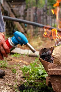 Ignition with a burner. A man sets fire to firewood with a gas burner. Breeding a fire. Travel skill. Cooking on a fire in the forest.