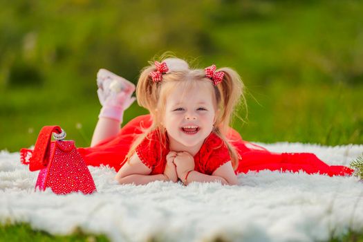 little girl in a red dress lies on a white blanket