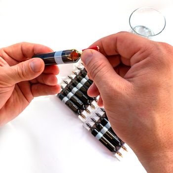 break off the tip of the ampoule. Group object of liquid medicinal agent in limpid glassware in medical laboratory. horizontal perspective view of many brown ampoules set in pharmaceutical packaging white container