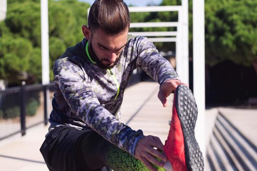 stylish sportsman stretching the leg on a railing, concept of healthy lifestyle and urban sport in the city, copy space for text