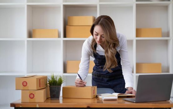 Portrait of Starting small businesses SME owners female entrepreneurs working on receipt box and check online orders to prepare to pack the boxes, sell to customers, sme business ideas online..