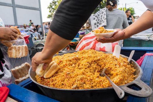 Street food sale in Managua Nicaragua, man serving Valencian rice with bread