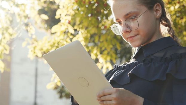 A teenage girl with a tablet in the park