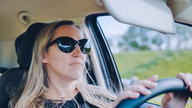 A young woman in a good mood behind the wheel of a car