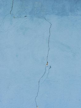 Vertical photo of an old cracked wall in blue.