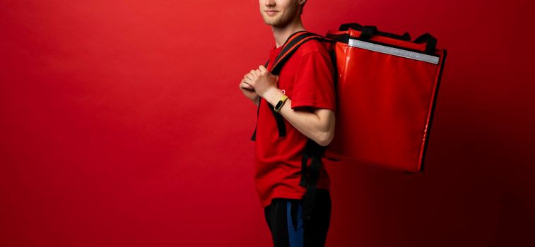 Young handsome happy smiling courier guy, food delivery man with red thermo box for food delivering food