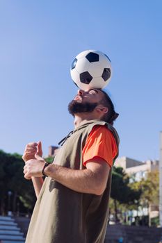 vertical portrait of a soccer player playing balancing the ball on his head , concept of healthy lifestyle and urban sport in the city, copy space for text