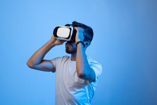 Bearded young man using VR glasses, touching with a hand copy space free space, playing virtual video games with friends online