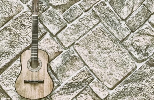 a brief record of facts, topics, or thoughts, written down as an aid to memory. a stringed musical instrument, with a fretted fingerboard. acoustic guitar on gray brick wall. High quality photo