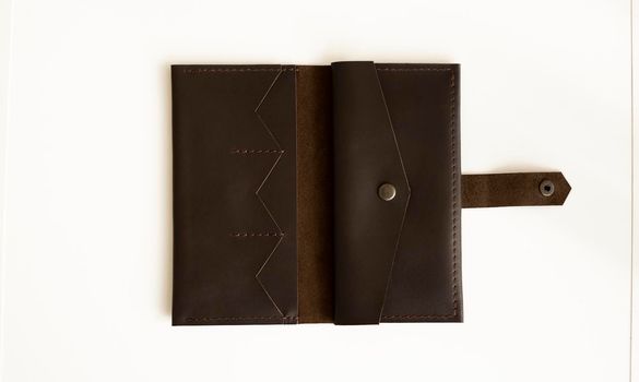 Man's handmade wallet on a white surface. Wallet made of genuine brown leather on a white background. Accessories for men