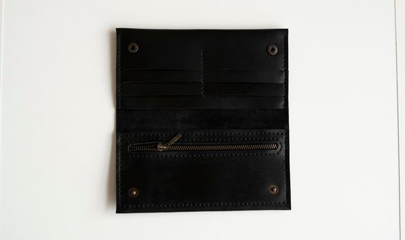 Man's handmade wallet on a white surface. Wallet made of genuine black leather with a slots for cards and big zip pocket on a white background. Accessories for men