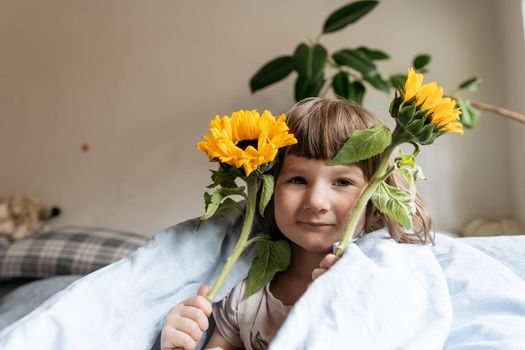 Portrait of a toddler girl holding sunflowers. High quality photo