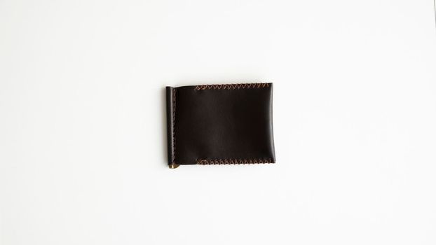 Brown men's money clip handmade leather wallet. Empty money clip wallet with a two pockets for cards lies on a white table. Selective focus, copy space