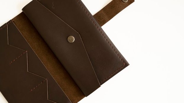 Man's handmade wallet on a white surface. Wallet made of genuine brown leather on a white background. Accessories for men