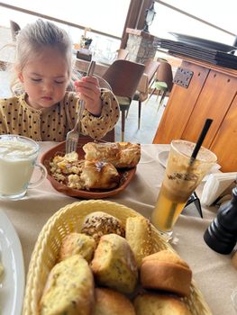 Little girl eating gibanica with a fork in a restaurant. High quality photo