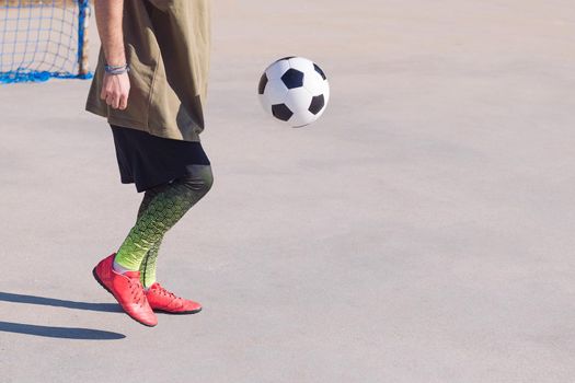 unrecognizable football player playing the ball in a concrete soccer field, concept of healthy lifestyle and urban sport in the city, copy space for text