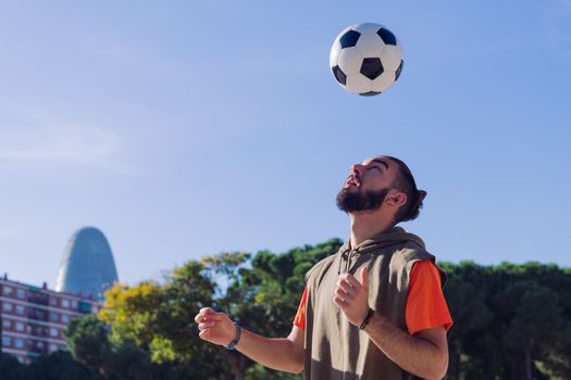 portrait of a football player playing giving head hits to the the ball in the city, concept of healthy lifestyle and urban sport in the city, copy space for text