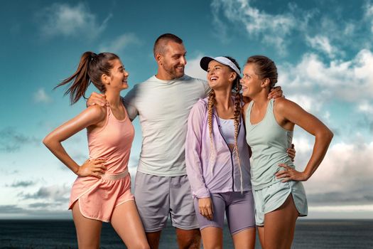 Smiling woman and man fitness team. A happy group of runners rest after running along the sea coast early in the morning