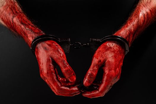 Close-up of male bloody handcuffed hands on a black background