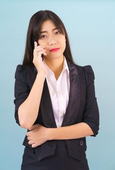 Young Asian women in suit standing posing using her phone against blue background