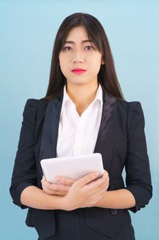 Young women standing in suit holding her digital tablet computor against blue background