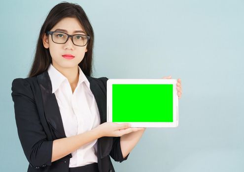 Young asian women in suit holding her digital tablet mock up standing against green background