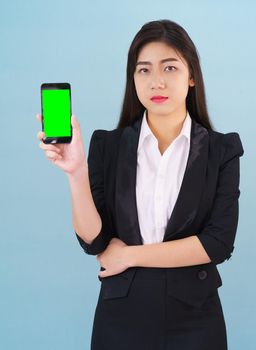 Young women in suit holding her green screen smartphone mock up standing against blue background