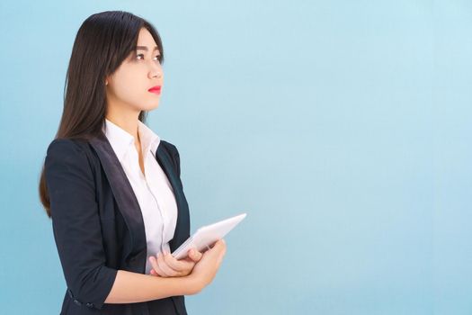 Young women standing in suit holding her digital tablet computor against blue background