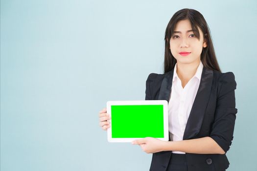 Young asian women in suit holding her digital tablet mock up standing against blue background