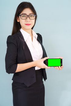 Young women in suit holding her  smartphone mock up green screen standing against blue background