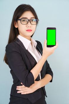 Young women in suit holding her  smartphone mock up green screen standing against blue background