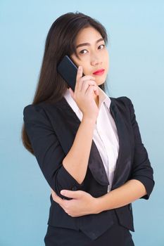 Young women in suit holding her phone standing against blue background