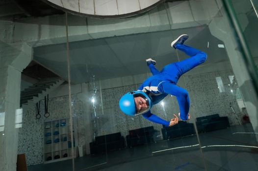 A man in overalls and a protective helmet enjoys flying in a wind tunnel. Free fall simulator.