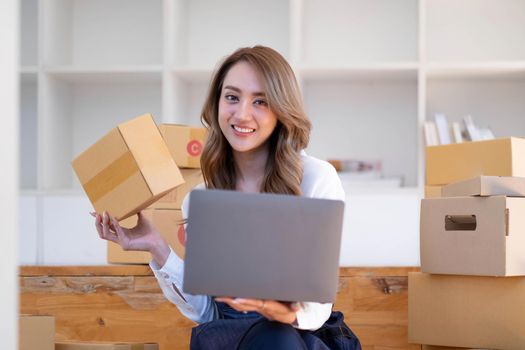 Portrait of Asian young woman SME working with a box at home the workplace.start-up small business owner, small business entrepreneur SME or freelance business online and delivery concept..