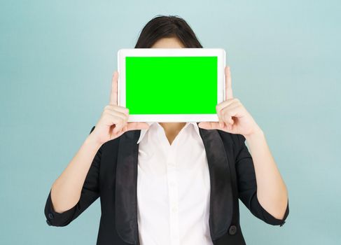 Young asian women in suit holding her digital tablet mock up standing against green background