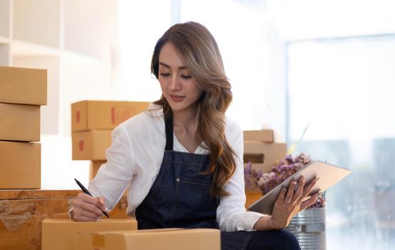 Portrait of Asian young woman SME working with a box at home the workplace.start-up small business owner, small business entrepreneur SME or freelance business online and delivery concept..