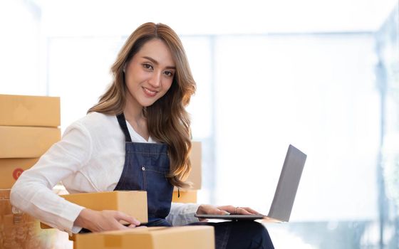 Portrait of Asian young woman SME working with a box at home the workplace.start-up small business owner, small business entrepreneur SME or freelance business online and delivery concept..