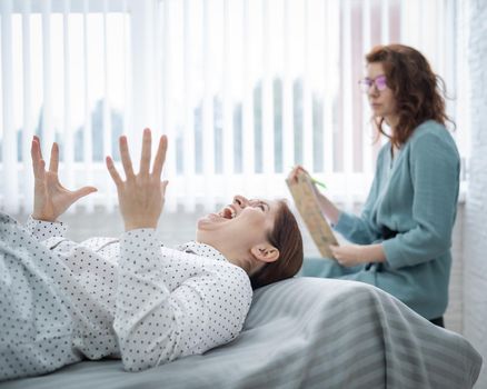 A middle-aged woman lies on a couch in a session with a psychoanalyst. Female patient in despair