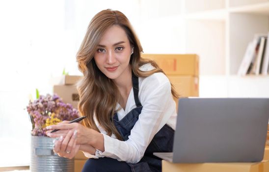 Portrait of Asian young woman SME working with a box at home the workplace.start-up small business owner, small business entrepreneur SME or freelance business online and delivery concept..