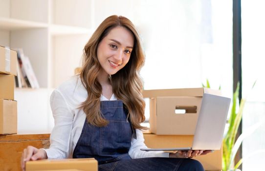 Portrait of Asian young woman SME working with a box at home the workplace.start-up small business owner, small business entrepreneur SME or freelance business online and delivery concept..