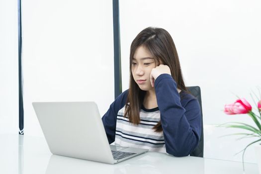 Young female student sitting in living room using laptop at desk learning online