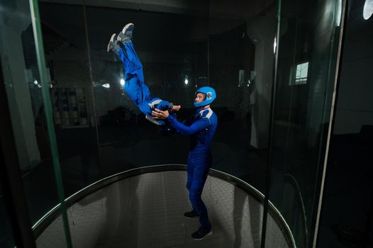 A man teaches a boy to fly in a wind tunnel. Lack of gravity