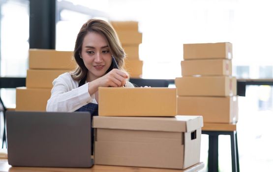 Portrait of Asian young woman SME working with a box at home the workplace.start-up small business owner, small business entrepreneur SME or freelance business online and delivery concept..