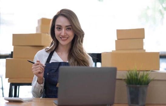 Portrait of Asian young woman SME working with a box at home the workplace.start-up small business owner, small business entrepreneur SME or freelance business online and delivery concept..