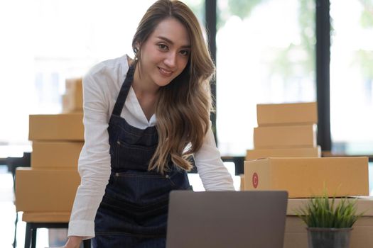 Portrait of Asian young woman SME working with a box at home the workplace.start-up small business owner, small business entrepreneur SME or freelance business online and delivery concept..