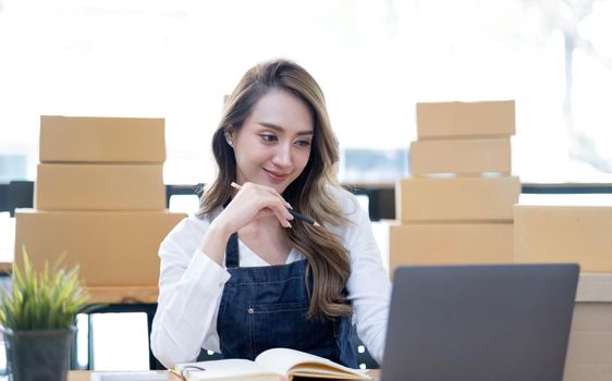 Portrait of Asian young woman SME working with a box at home the workplace.start-up small business owner, small business entrepreneur SME or freelance business online and delivery concept..